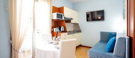 A compact living space with a dining area, kitchenette, and a sofa.