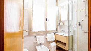 A modern bathroom with a toilet, bidet, sink, and shower.