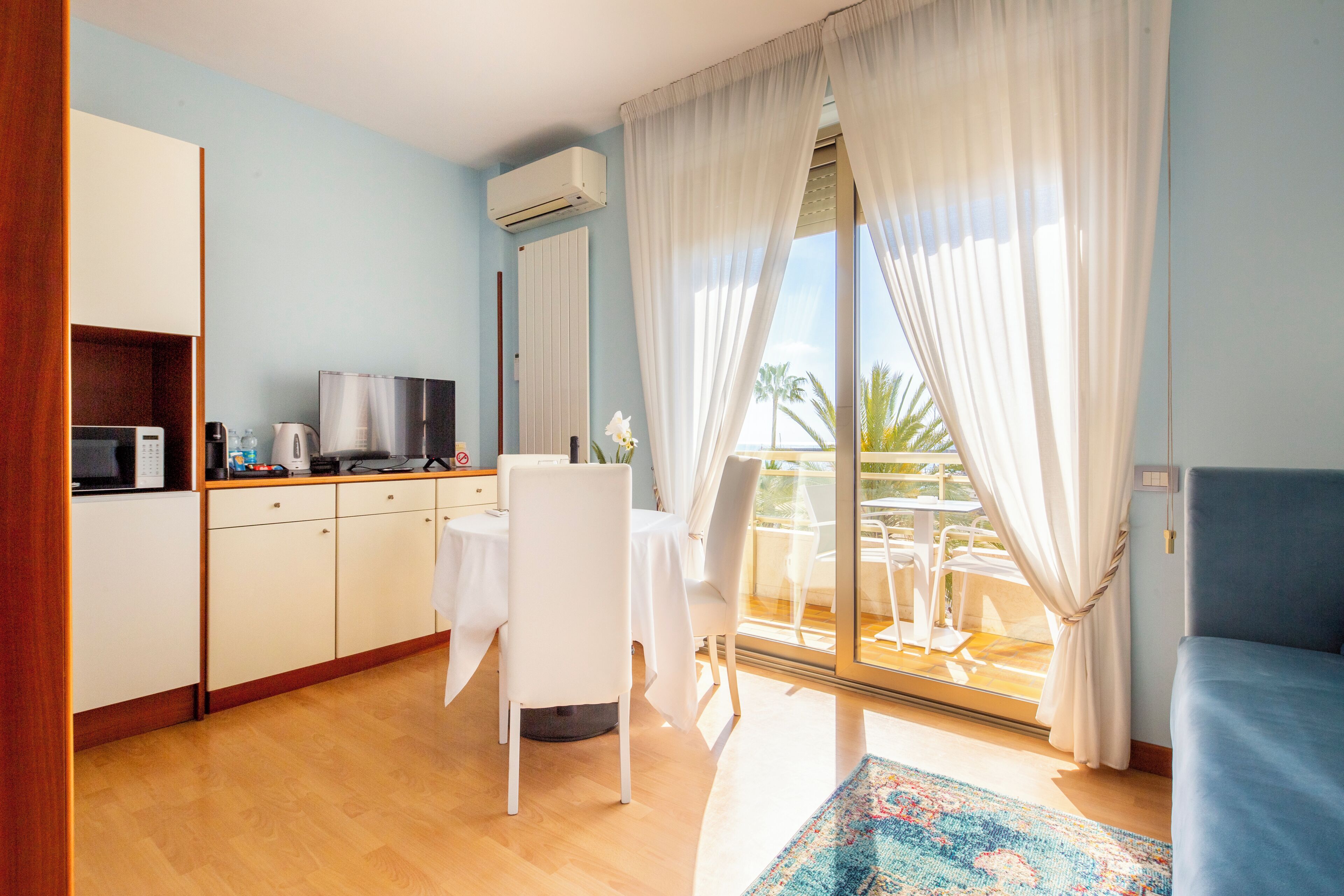 Una habitación de hotel moderna con kitchenette, comedor y balcón con vistas.