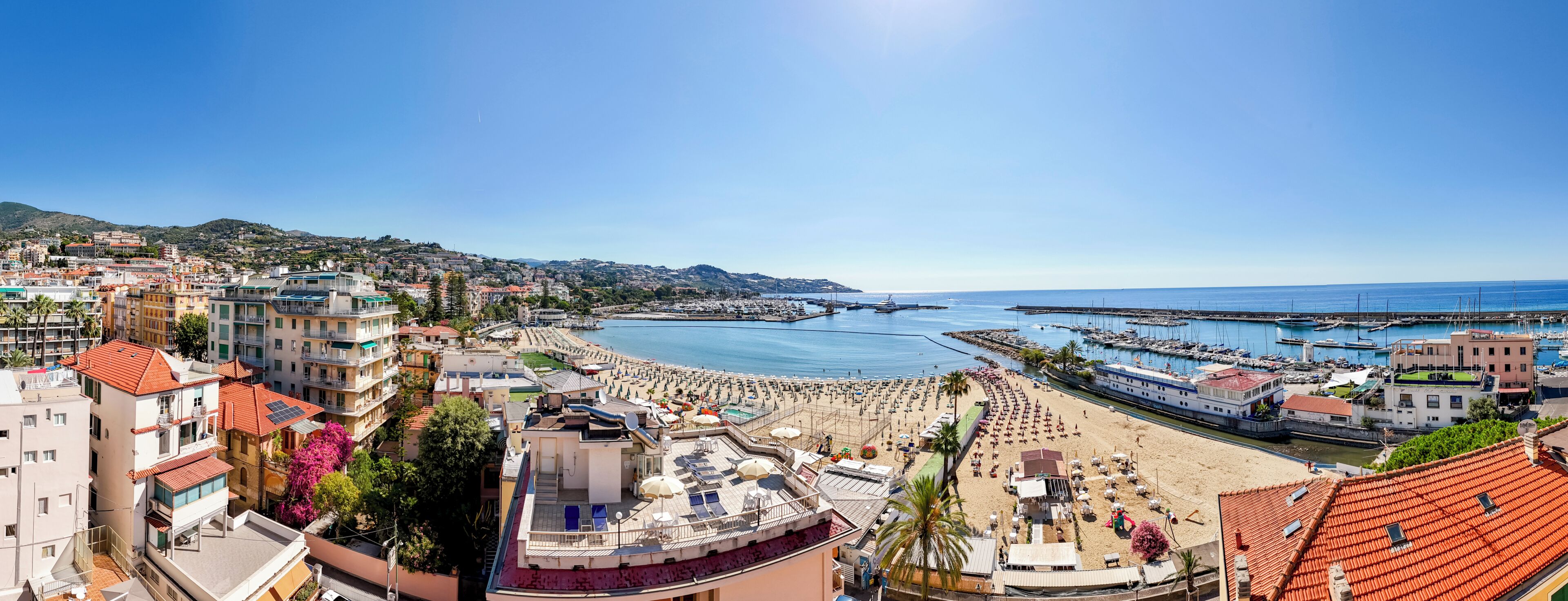 A coastal cityscape with a marina, beach, and residential buildings.