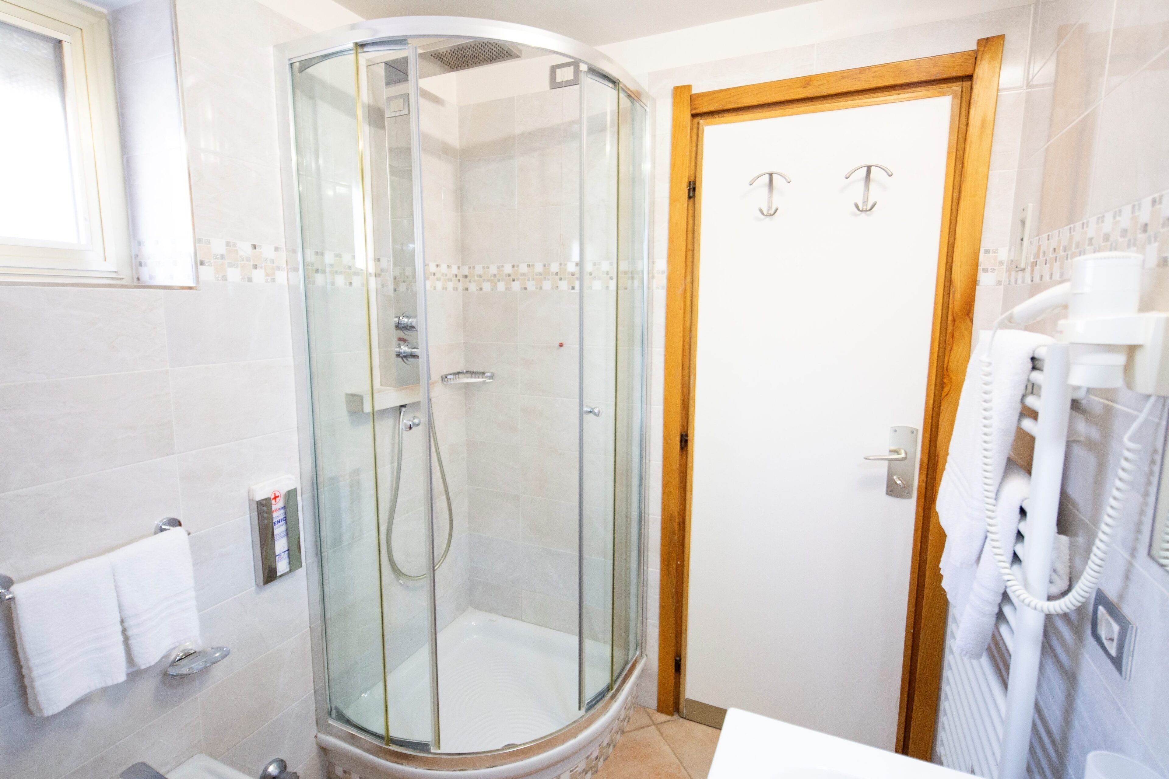 Un baño con ducha de vidrio, un lavabo blanco y un perchero para toallas.