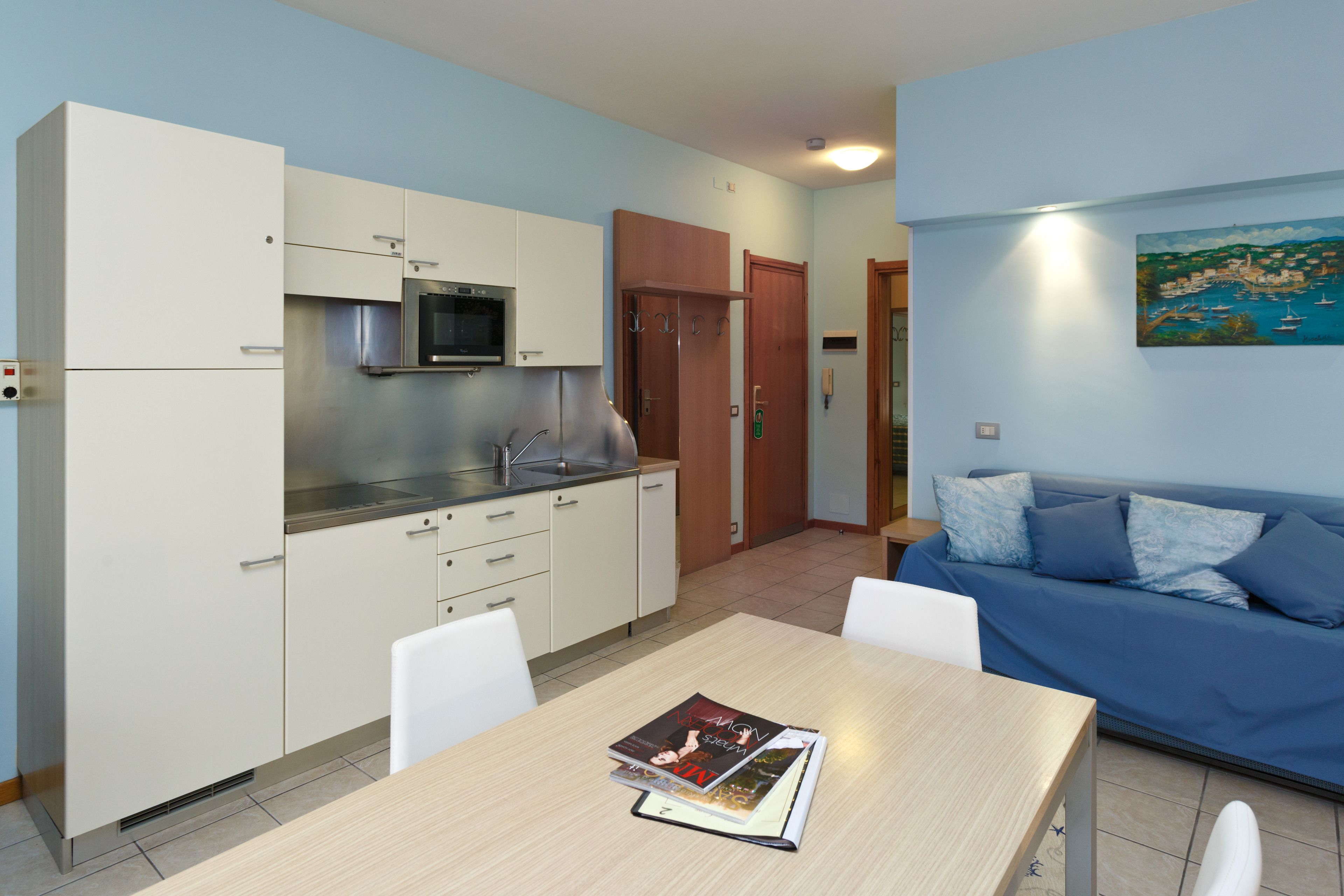 Un espacio habitable compacto con kitchenette, una mesa de comedor y un sofá.