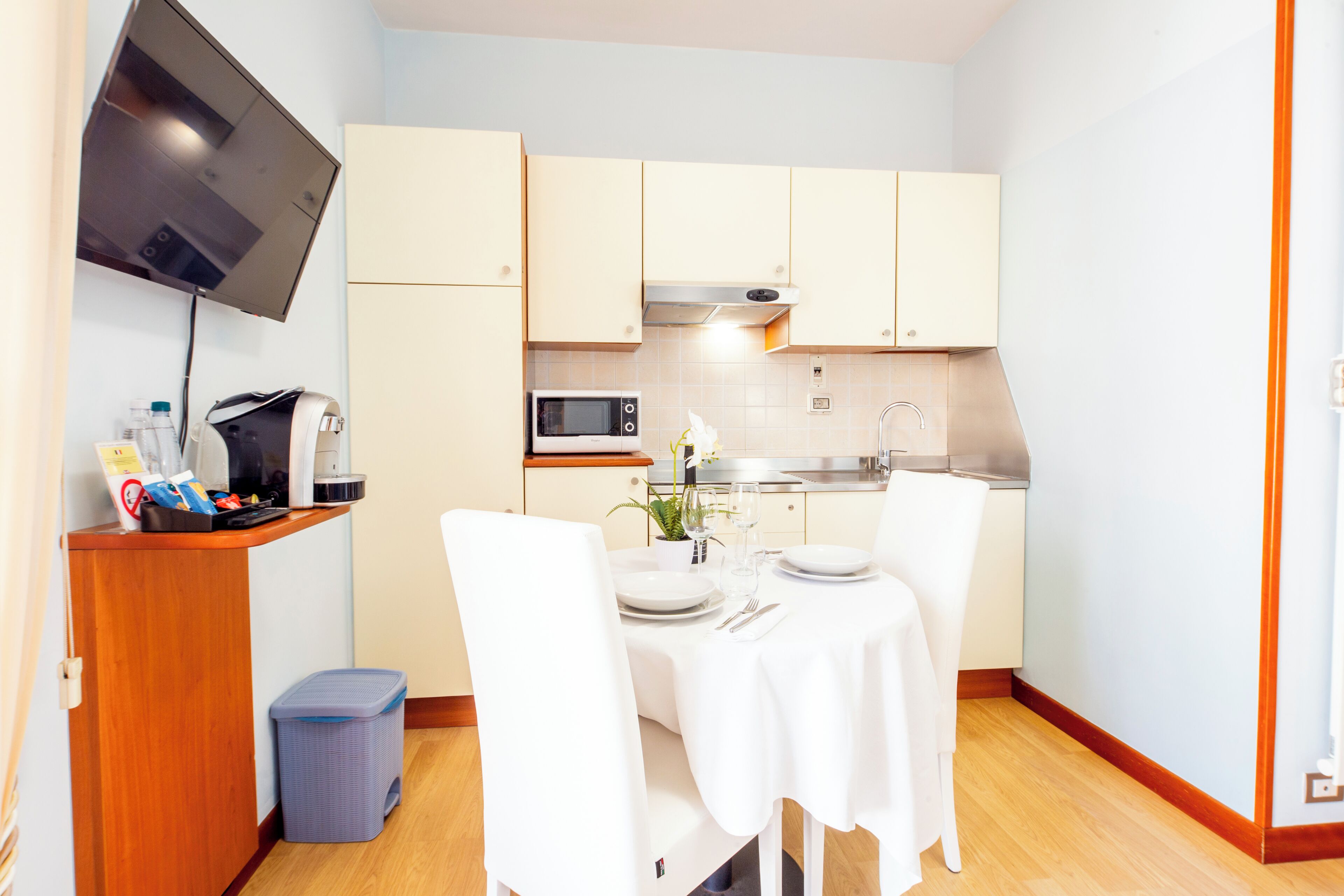 Une cuisine compacte comprenant une table à manger pour deux personnes, un four à micro-ondes et un évier.