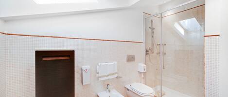A modern bathroom with a bidet, toilet, and glass-enclosed shower.