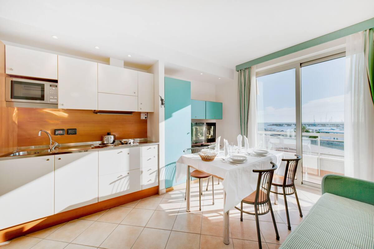 A modern kitchen with white cabinets, a microwave, and a dining area with a table set for two.