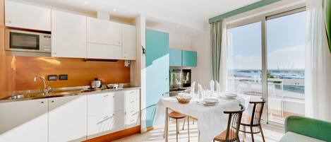 Une cuisine moderne avec des meubles blancs, un four à micro-ondes et un coin repas avec une table dressée pour deux personnes.