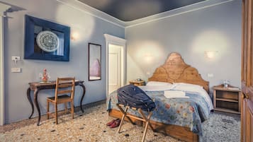 Un dormitorio con una cama de madera, un escritorio con silla, un espejo y un suelo estampado.