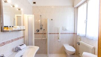 A modern bathroom with a glass-enclosed shower, a white sink, and a toilet.