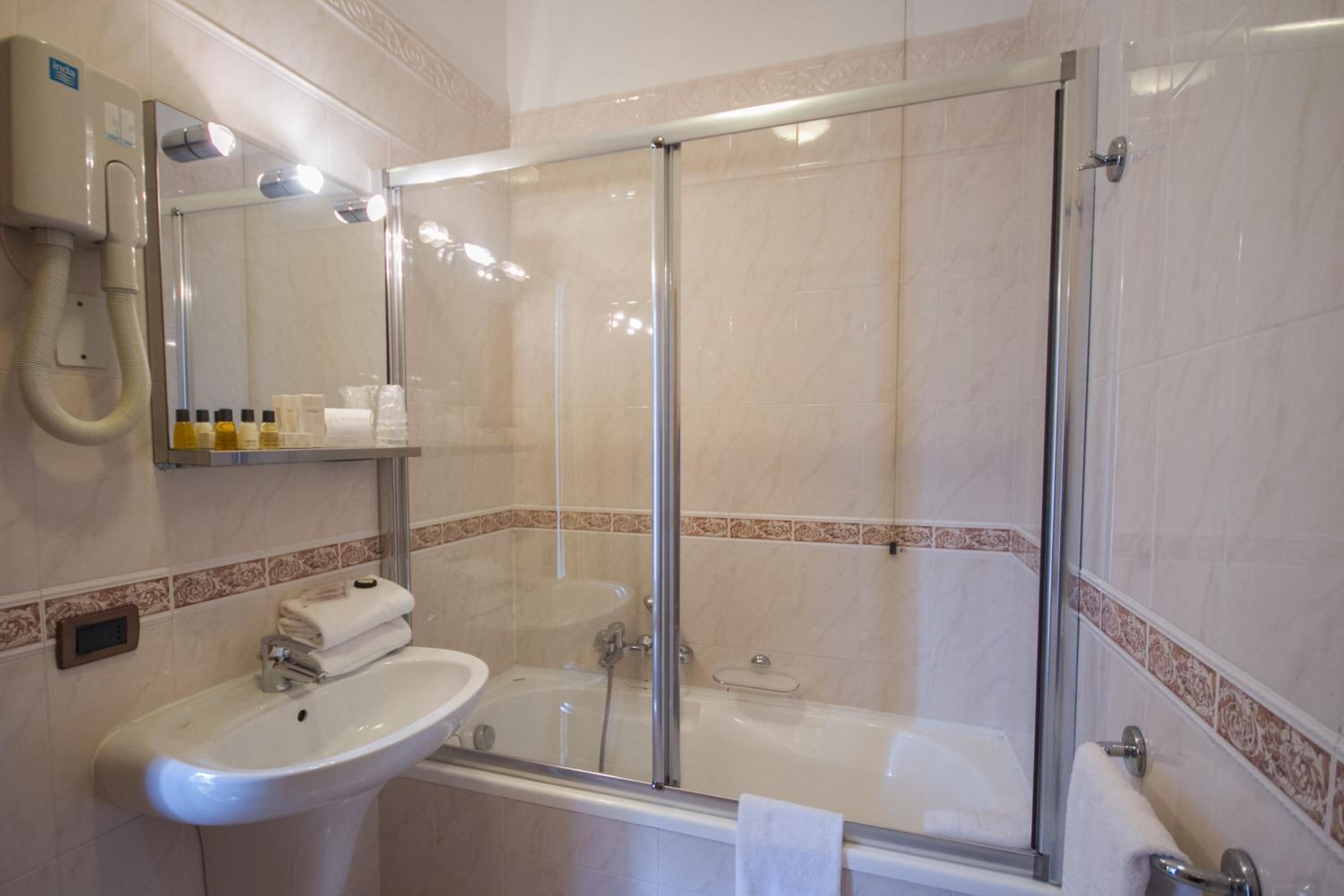 Un baño con ducha de vidrio, lavamanos y espejo.