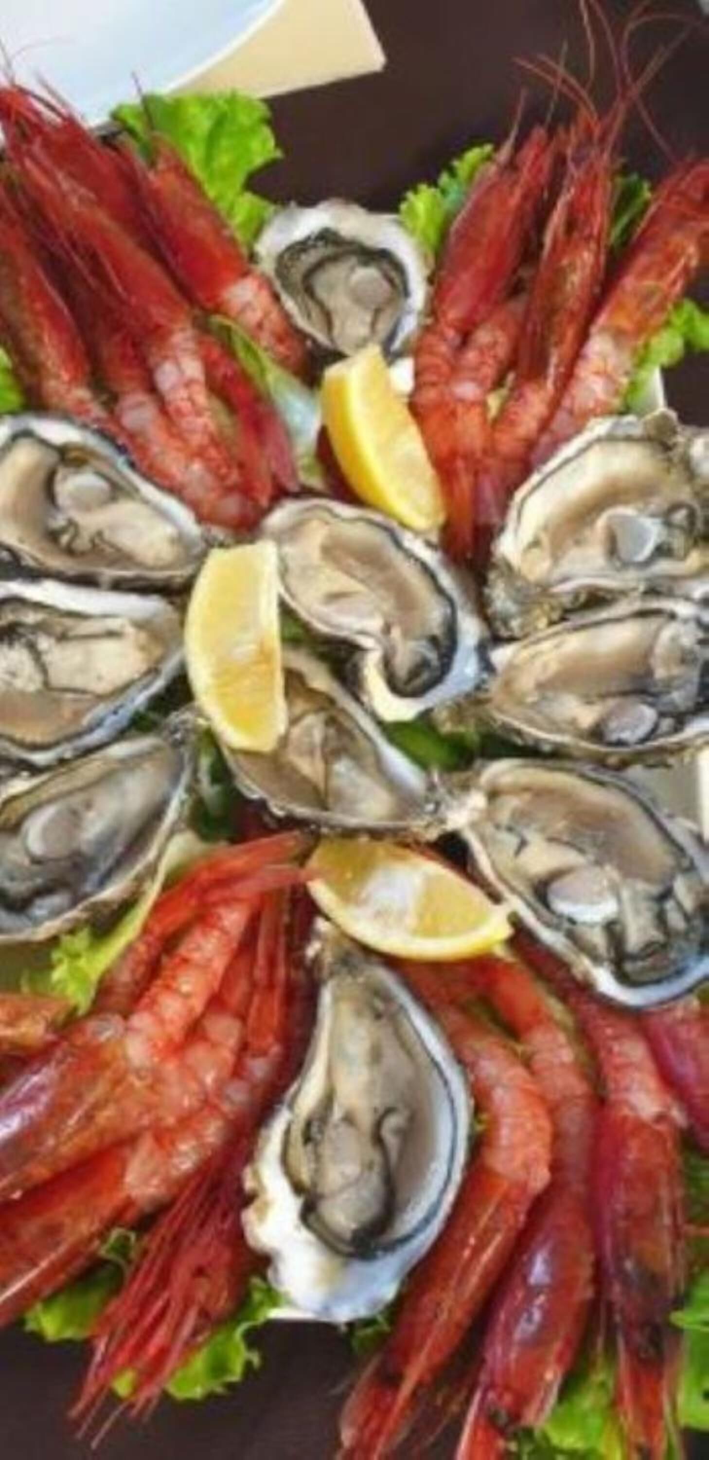 Un plateau de fruits de mer composé de crevettes et d’huîtres, servi sur un lit de laitue.