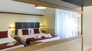 Een hotelkamer met twee bedden, een grote spiegel en een raam met gordijnen.