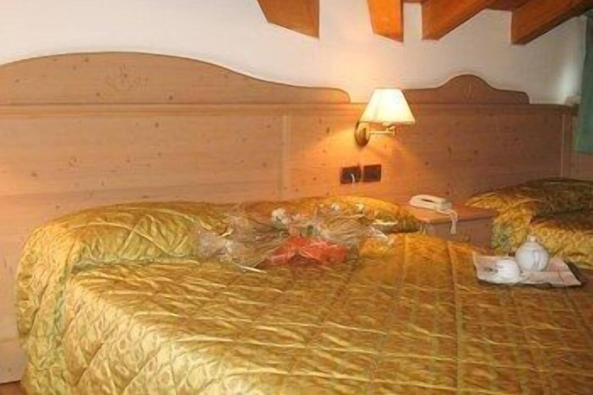 Ein Hotelzimmer mit einem Holzkopfteil, einer Nachttischlampe und einem Bett mit einer Steudecke.