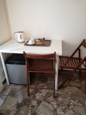 Cozy retreat with a compact kitchenette, featuring a kettle, cup, and refrigerator.