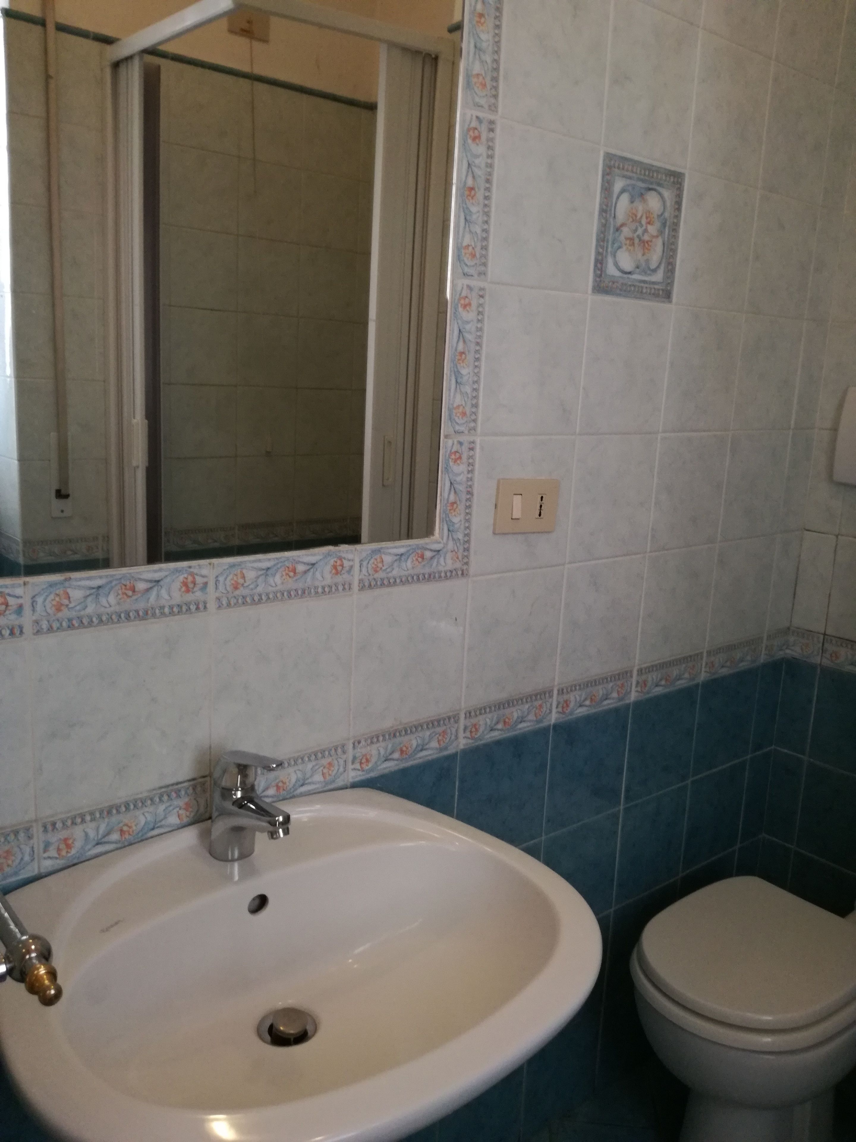 A bathroom with a white sink, a toilet, and a mirror.