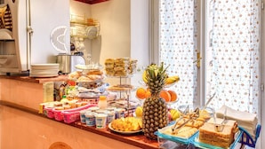 Un buffet proposant une variété de plats, notamment des fruits, des sandwichs et des desserts, disposés sur un comptoir avec une fenêtre en arrière-plan.