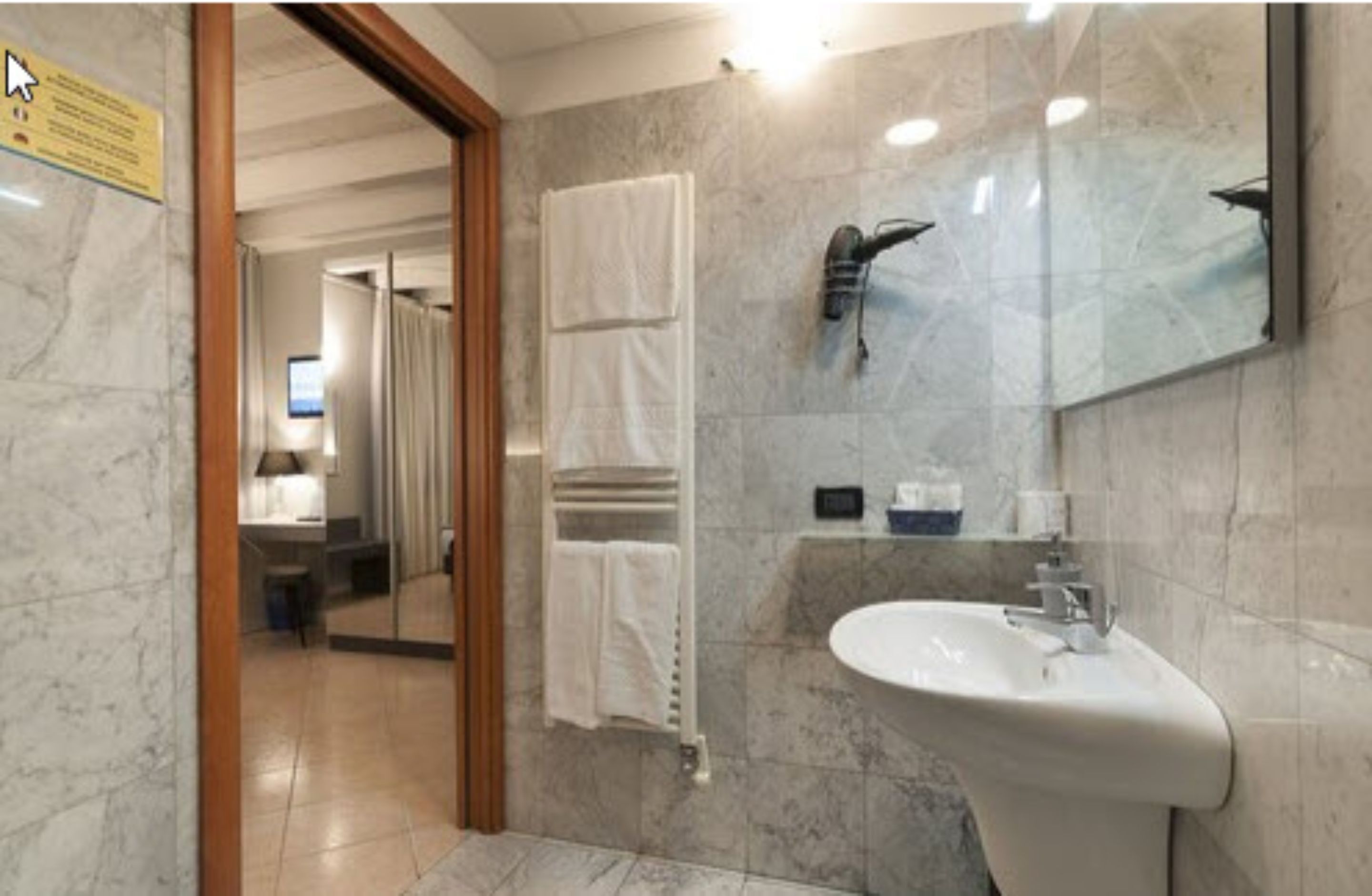 A modern bathroom with a marble floor, a white sink, a towel rack, and a mirror.