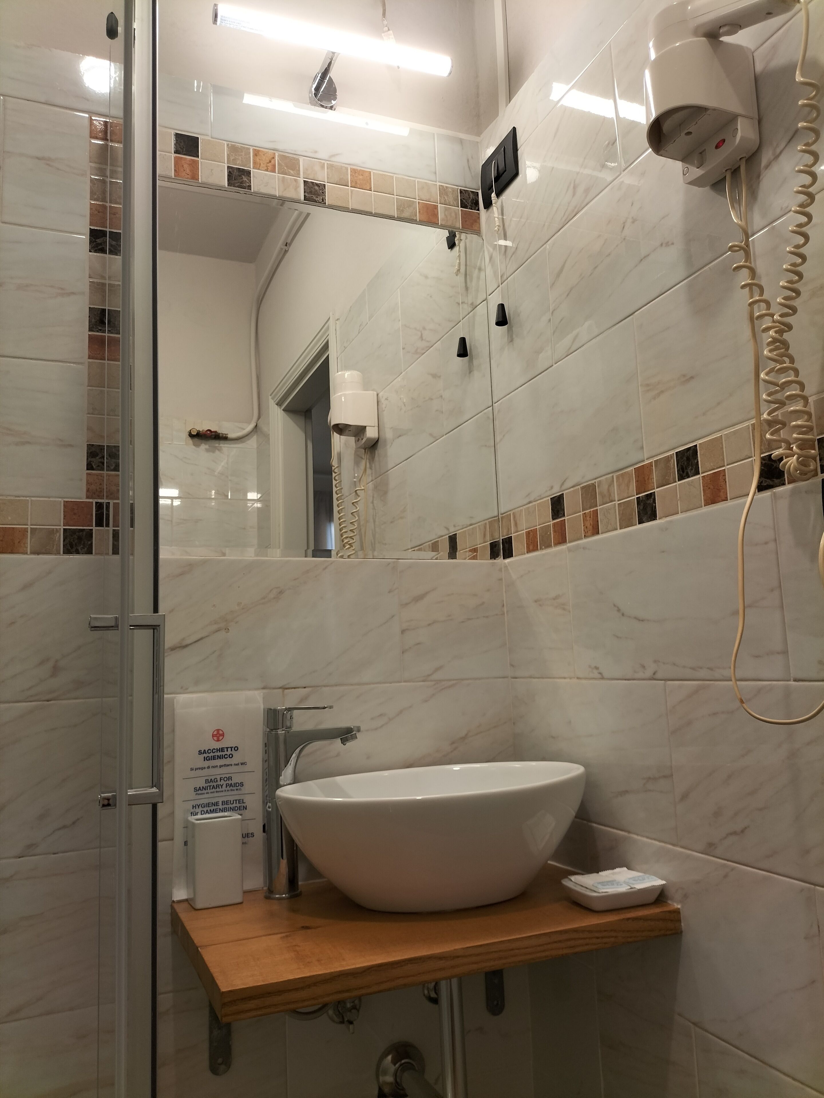 A bathroom with a white sink, a mirror, a shower, and a towel rack.