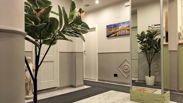 A hallway with a marble floor, a large potted plant, a statue, and a painting on the wall. - Hotel Camilla Guelfa (Florence)