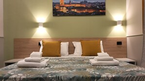 A hotel room with a bed, two pillows, a nightstand, and a wall-mounted picture of a cityscape. - Hotel Camilla Guelfa (Florence)