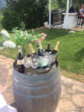 En träfat fylld med champagneflaskor och glas, placerad utomhus på en uteplats.