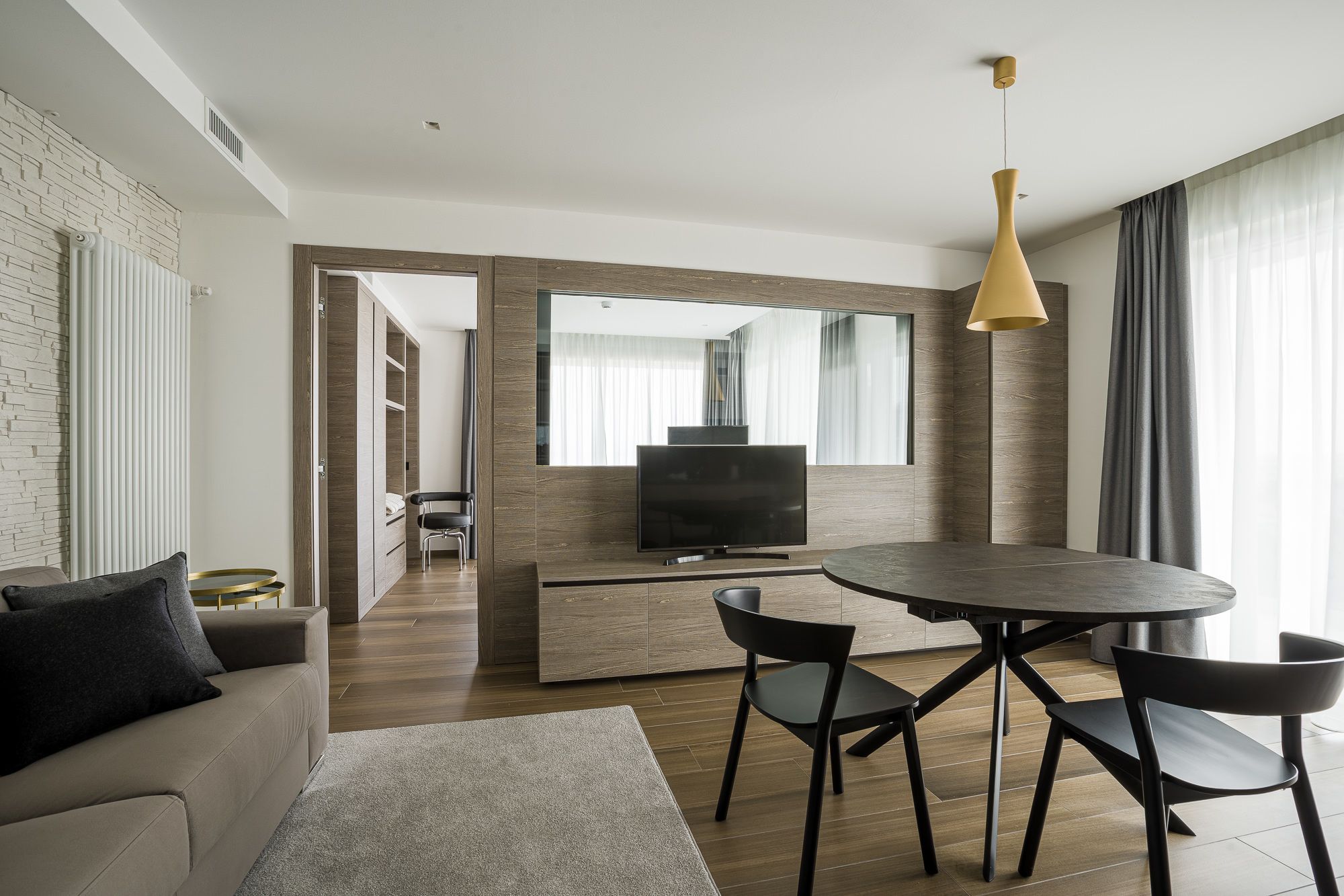 Una sala de estar moderna con un sofá, una mesa de comedor redonda con sillas, un televisor y un espejo grande.