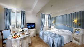 Une chambre d’hôtel avec un lit, une télévision, une table où le petit-déjeuner est servi, et une vue sur la ville.