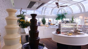 Una cocina moderna con una isla central, una fuente de chocolate y diversas plantas.