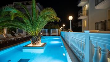 Ein Swimmingpool mit einer Palme, Liegestühlen und einer weißen Brüstung.