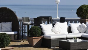 Una terraza con sofá, sillas y mesa, con vista a un cuerpo de agua.
