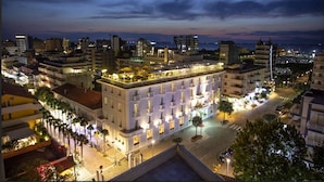 Un hotel con terraza en la azotea, varios pisos y un patio central.