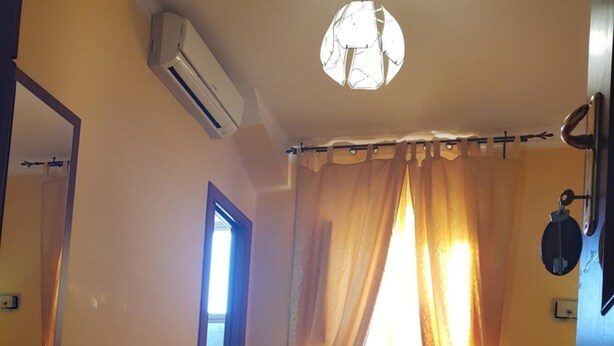 A bedroom with a bed, a door, an air conditioning unit, a mirror, and a light fixture. - Rudy B&B (Rome)