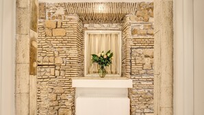 A stone wall with a white bench and a framed mirror above it. - Pantheonview - Luxury Suites (Rome)