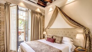A hotel room with a large bed, a nightstand with a lamp, and a view through a glass door. - Pantheonview - Luxury Suites (Rome)