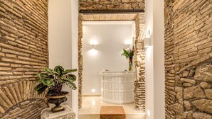 A stone-walled hallway with a checkered floor leading to a white door. - Pantheonview - Luxury Suites (Rome)