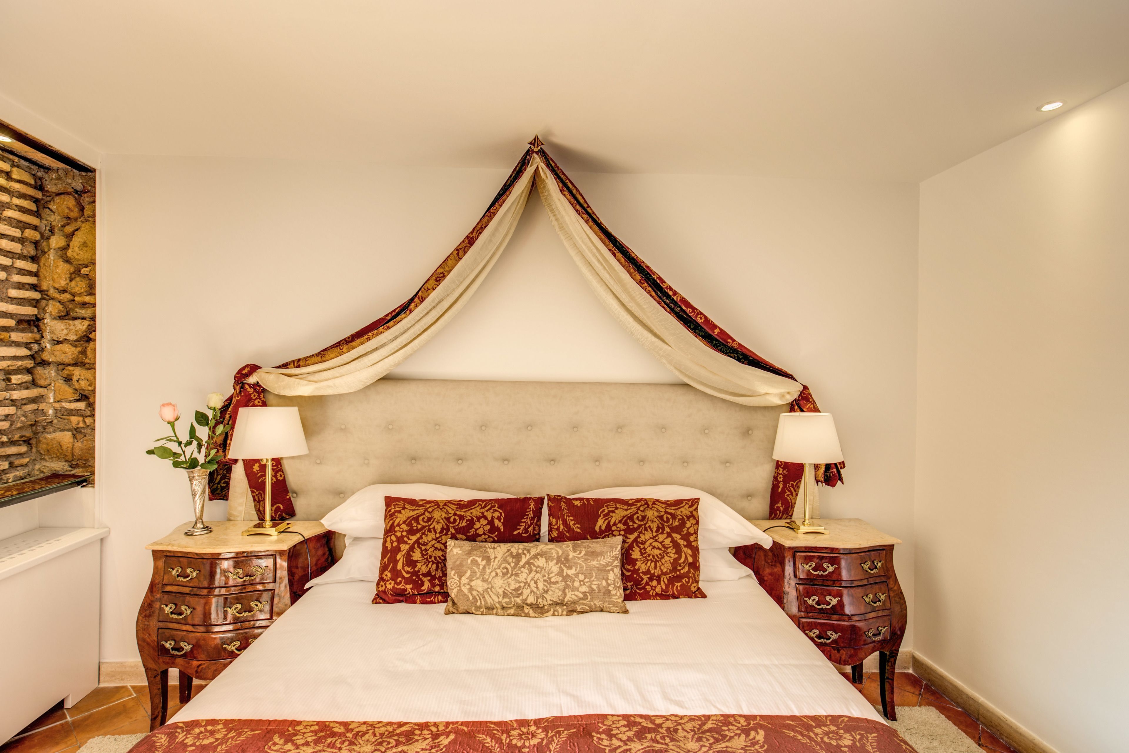 Una camera da letto con un letto a baldacchino, due comodini e un muro in pietra.