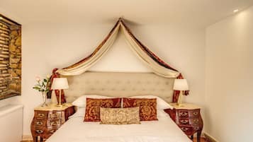 Una camera da letto con un letto a baldacchino, due comodini e un muro in pietra.