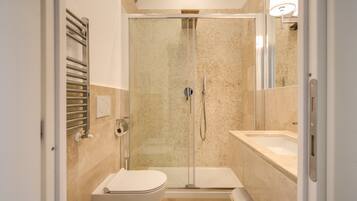 Une salle de bain moderne dotée d’une douche à parois de verre, de toilettes et d’un lavabo.