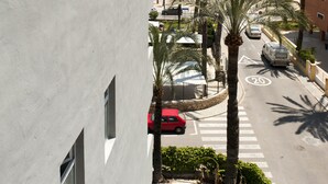 A modern building with a pool, a street with palm trees, and a beach in the background. - Hotel El Palmeral (Benidorm)