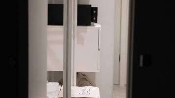 Ein Zimmer mit weißem Schreibtisch, einem an der Wand montierten Kleiderhaken und einem weißen Kleiderschrank.