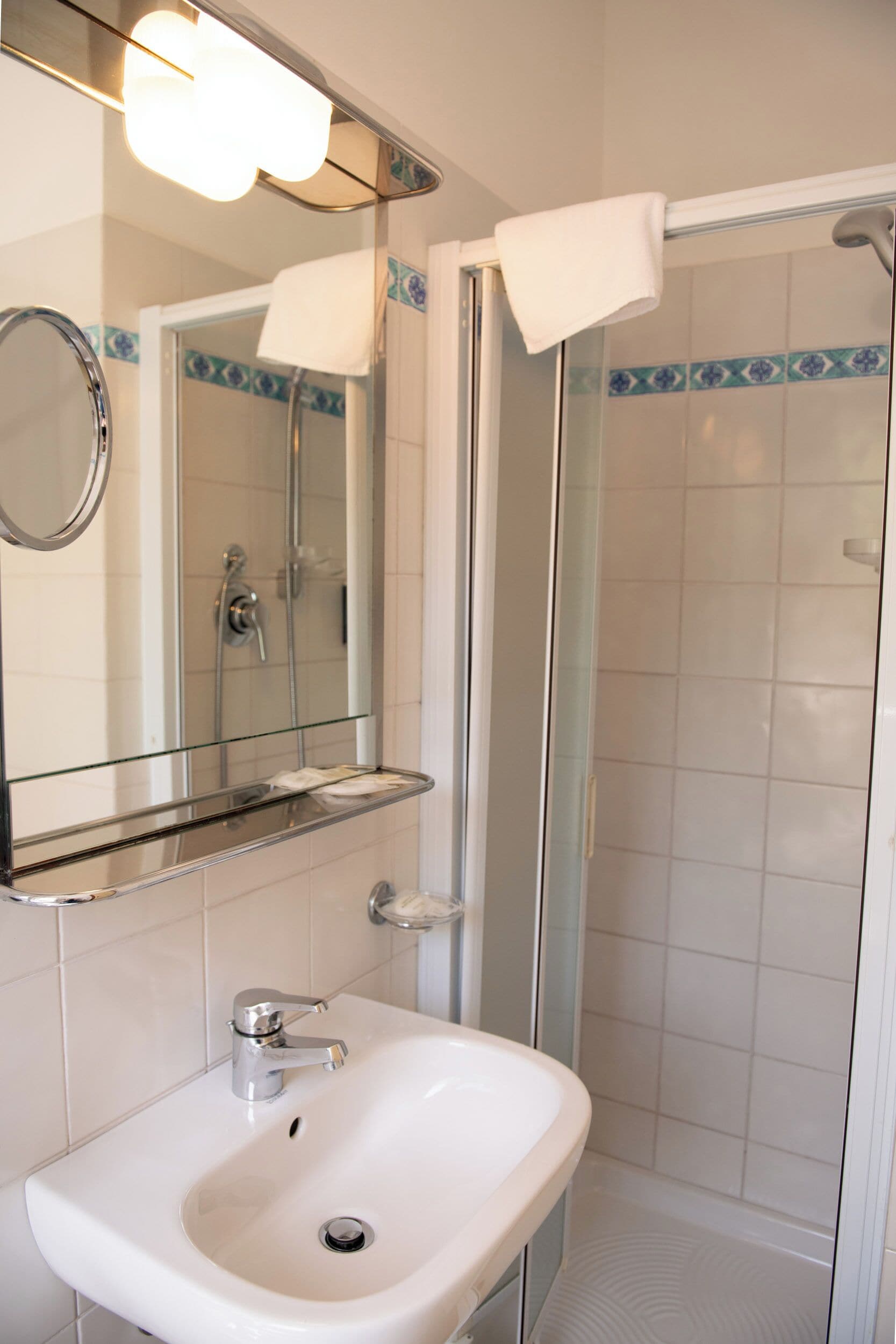 A bathroom with a white sink, a mirror, and a glass-enclosed shower.