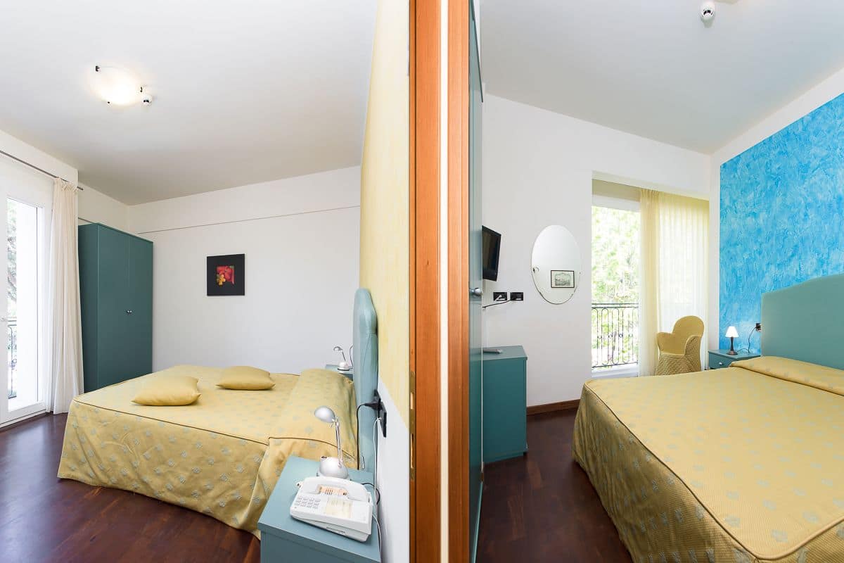 Habitación de hotel con dos camas, un escritorio, una silla, un televisor y una ventana con cortinas.
