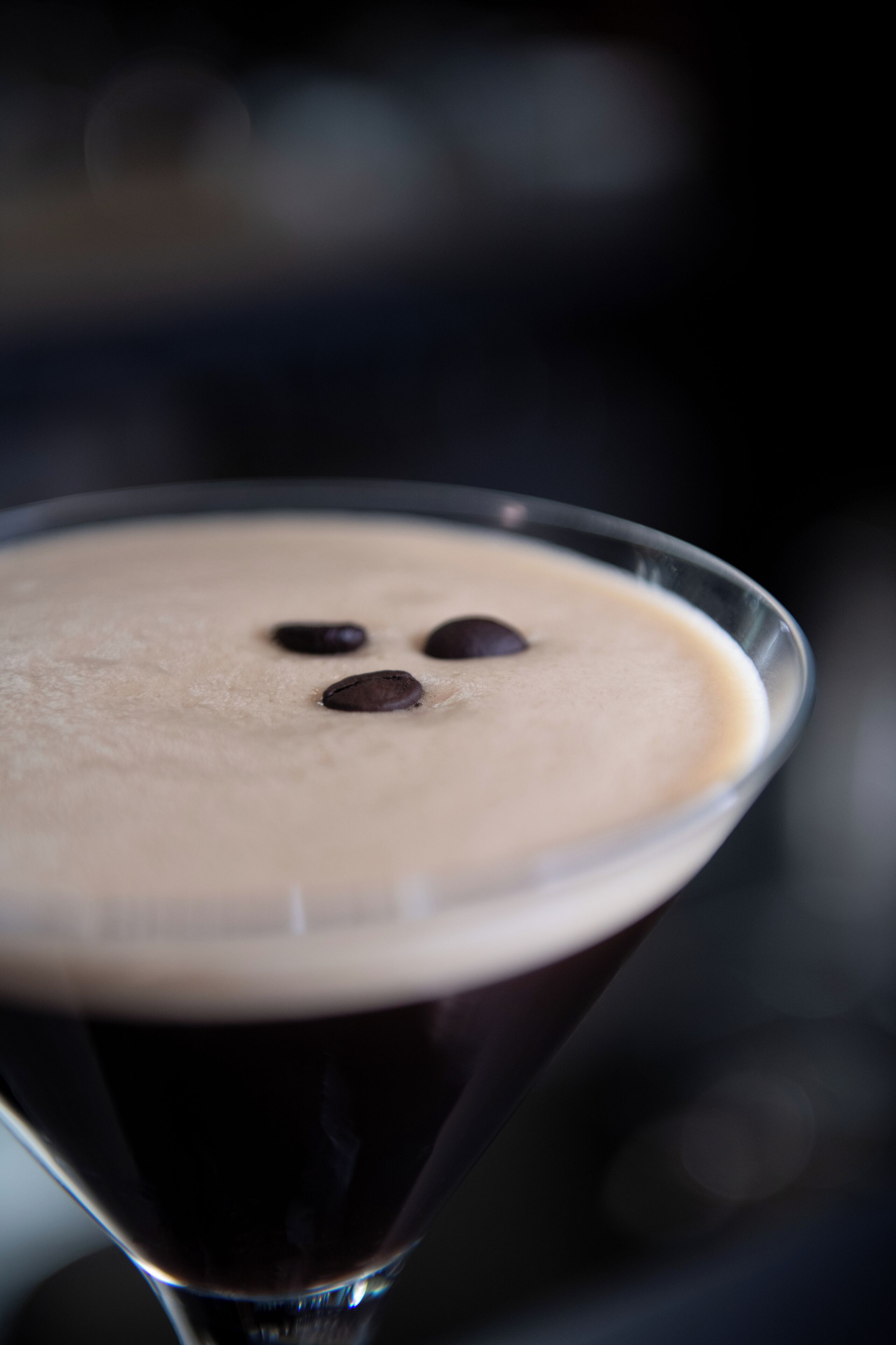 Un primo piano di un bicchiere da martini con una schiuma in superficie e scaglie di cioccolato.