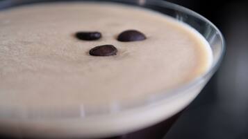 Un primo piano di un bicchiere da martini con una schiuma in superficie e scaglie di cioccolato.