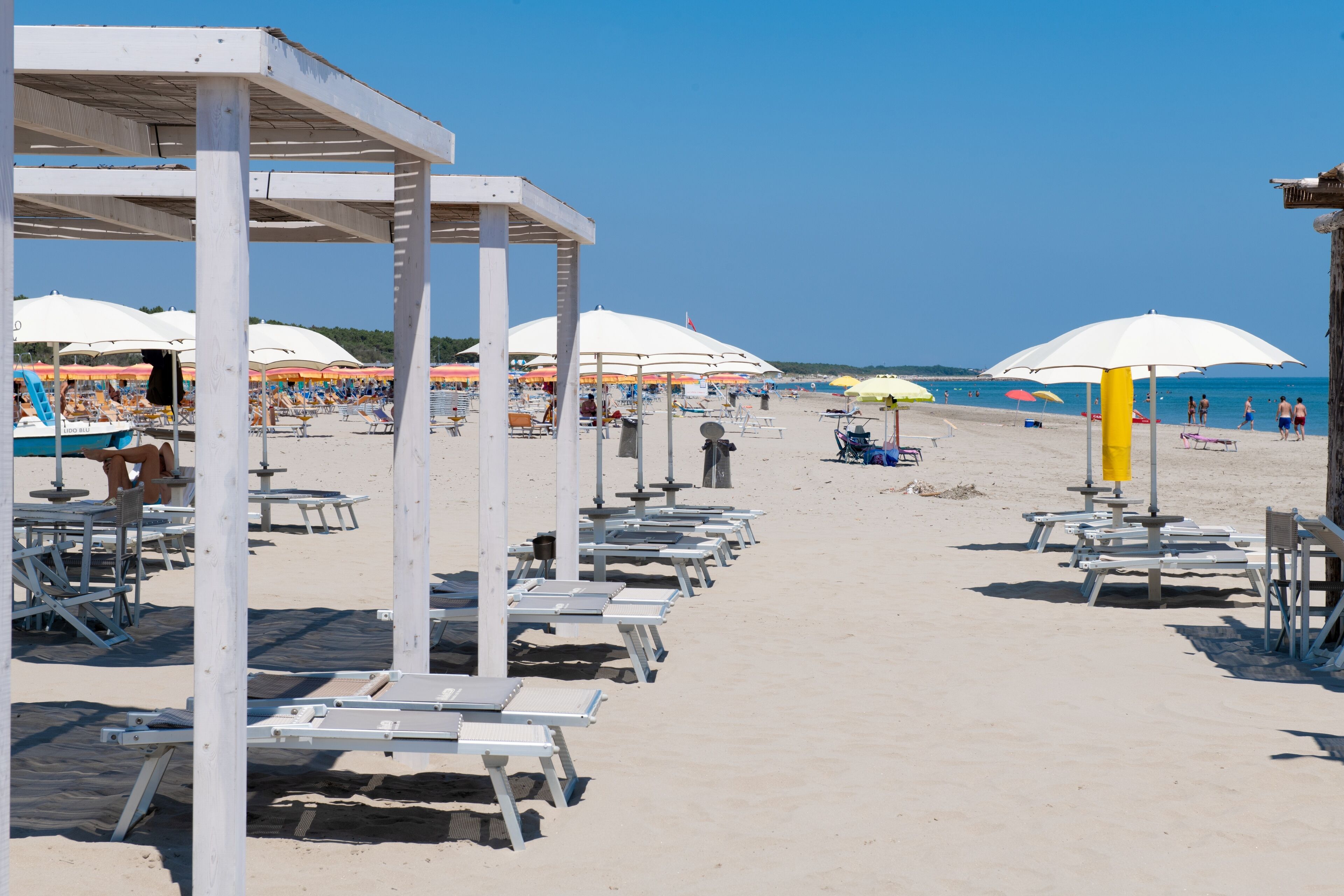 Une plage bordée de rangées de transats et de parasols, avec une tour de surveillance et des chaises de plage.