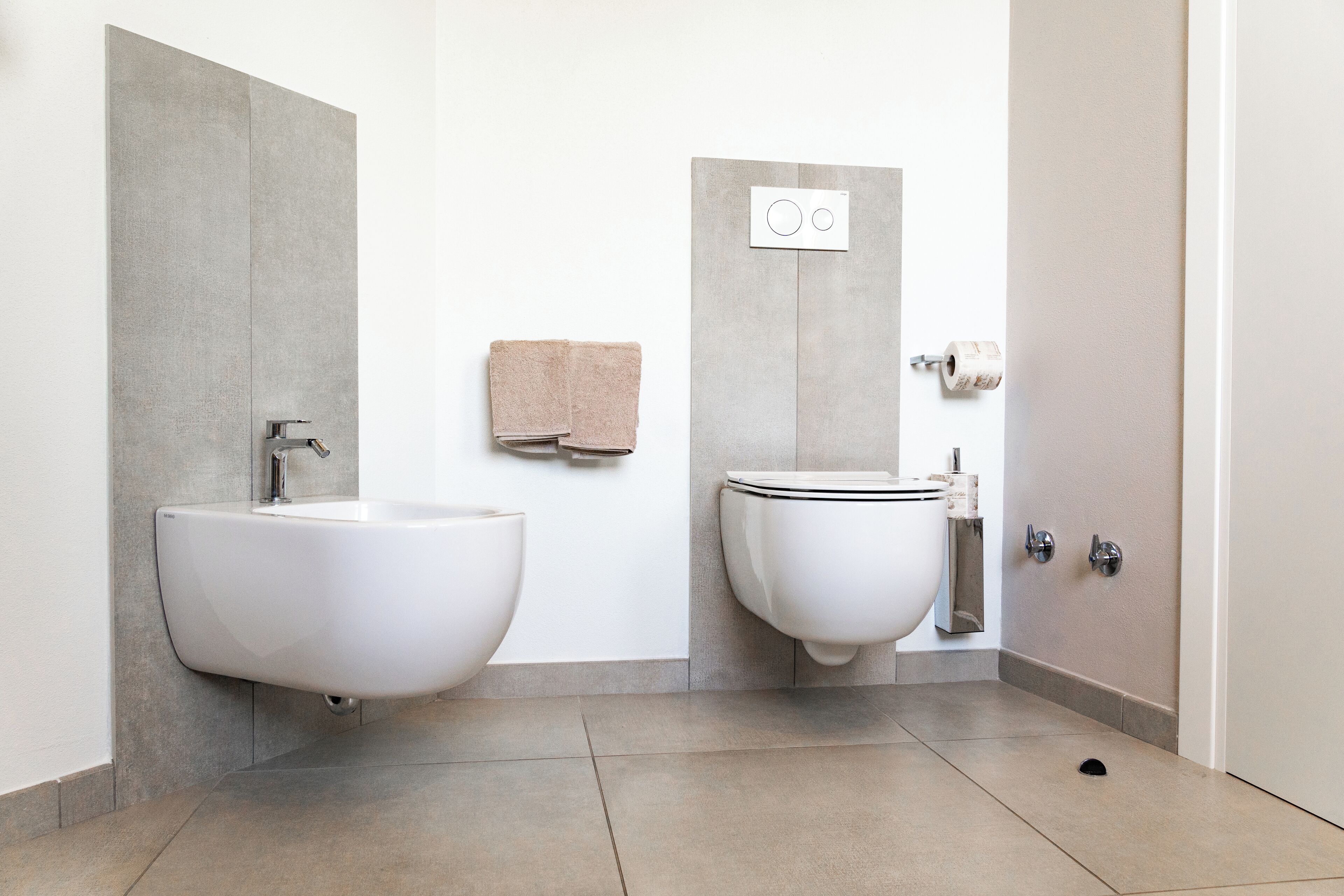 Un bagno moderno con due lavabi, un water e un portasciugamani.