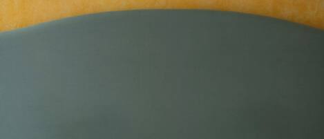 A bed with a green headboard and a beige mattress.