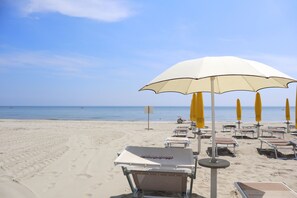 På stranden, hvit sand, solsenger og parasoller