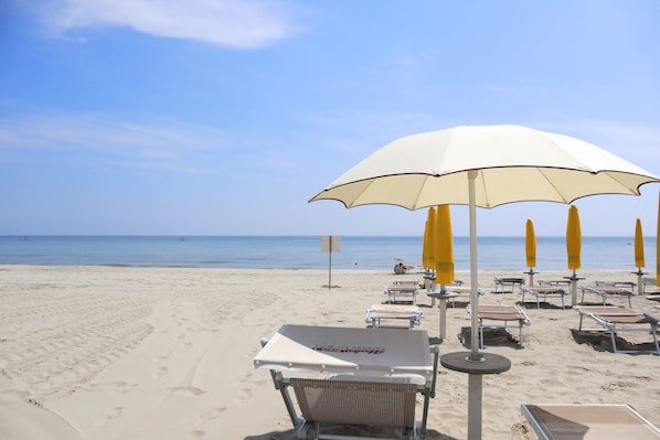 Am Strand, weißer Sandstrand, Liegestühle, Sonnenschirme
