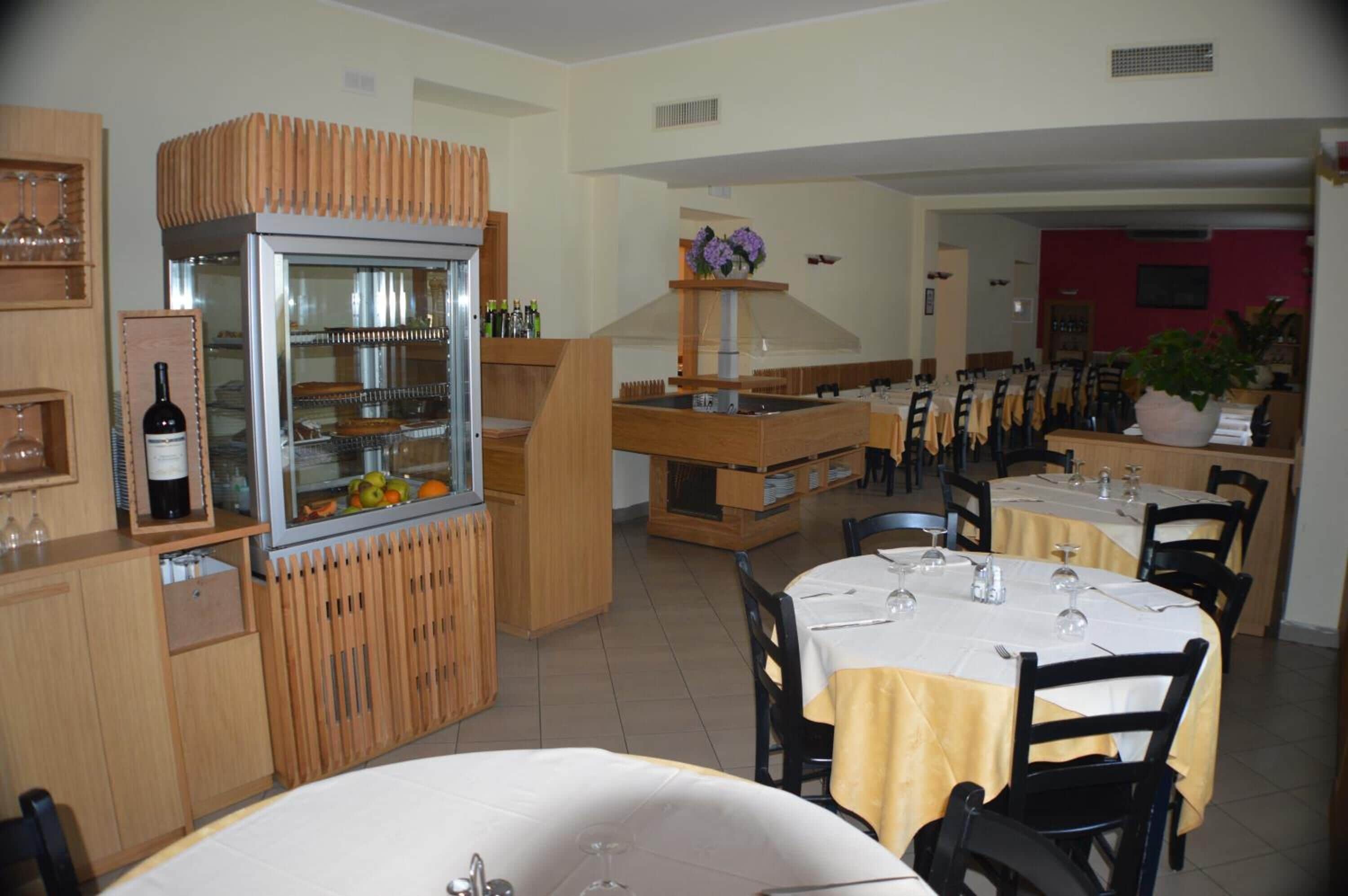 A restaurant with wooden furniture, a glass display case with food, and tables set for dining.
