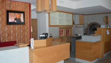 A reception area with a television, wooden reception desk, and a menu board.